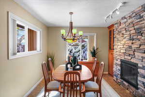 Tiled dining area featuring a fireplace, rail lighting, a textured ceiling, and a notable chandelier