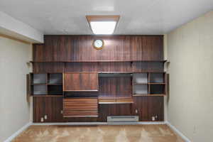 Unfurnished bedroom featuring light carpet, built in desk