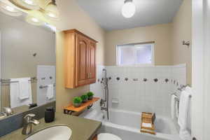 Bathroom featuring vanity, a bathing tub, toilet, a textured ceiling, and tile walls