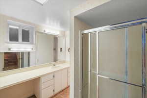 Bathroom with tile patterned floors, a shower with door, vanity, and a textured ceiling