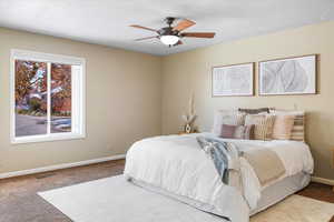 Bedroom with carpet, ceiling fan, and a textured ceiling