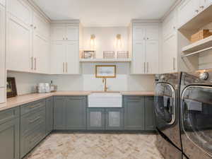 Laundry room with washing machine and clothes dryer, sink, and cabinets