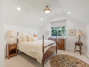 Bedroom with light carpet and vaulted ceiling