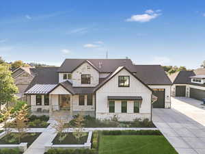 Modern inspired farmhouse featuring a garage and a front lawn