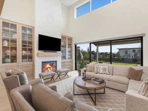 Living room with a fireplace, a high ceiling, and light wood-type flooring