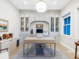 Office space with light wood-type flooring and an inviting chandelier