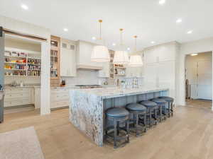 Kitchen featuring a large island, hanging light fixtures, tasteful backsplash, a barn door, and light wood-type flooring