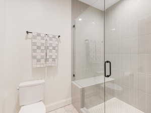 Bathroom with tile patterned floors, toilet, and a shower with shower door