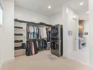 Spacious closet with light colored carpet and stacked washer and clothes dryer