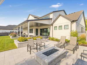 Rear view of property featuring a yard, a patio, and an outdoor living space with a fire pit