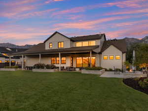 Back house at dusk featuring a patio area, a mountain view, a yard, and a fire pit