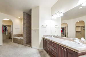 Bathroom featuring a textured ceiling, vanity, and separate shower and tub