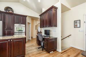 Office area with light hardwood / wood-style floors and vaulted ceiling