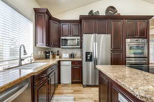 Kitchen featuring stainless steel appliances, a wealth of natural light, lofted ceiling, and sink