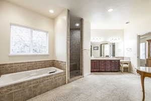 Bathroom featuring vanity, a textured ceiling, and plus walk in shower