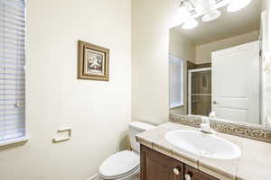 Bathroom featuring a shower with door, vanity, and toilet