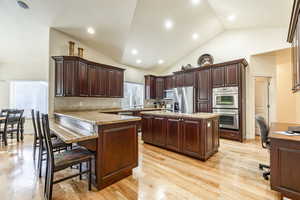 Kitchen featuring stainless steel appliances, kitchen peninsula, decorative backsplash, a kitchen island, and light wood-type flooring