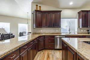 Kitchen with pendant lighting, sink, stainless steel dishwasher, light wood-type flooring, and tasteful backsplash