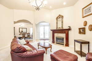 Living room featuring french doors, light carpet, a high end fireplace, and a chandelier