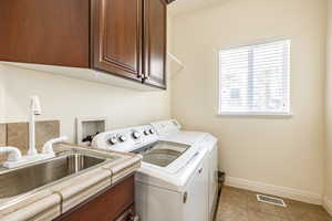 Laundry room featuring cabinets, sink, washer and clothes dryer, and light tile patterned flooring