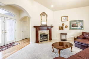 Living room featuring light wood-type flooring, a fireplace, and french doors