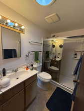 Bathroom featuring walk in shower, a textured ceiling, vanity, tile patterned flooring, and toilet