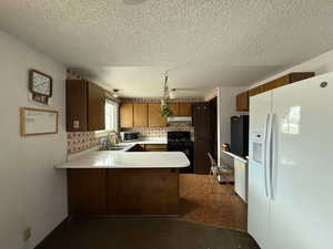 Kitchen featuring sink, black appliances, a textured ceiling, kitchen peninsula, and backsplash