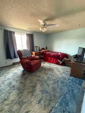 Carpeted bedroom featuring a textured ceiling and ceiling fan