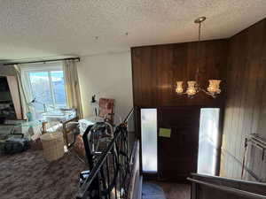 Carpeted entrance foyer featuring a textured ceiling and wooden walls