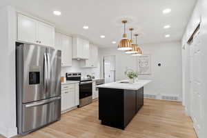 Kitchen with a center island with sink, light hardwood / wood-style floors, white cabinetry, and stainless steel appliances