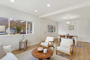 Sitting room featuring beam ceiling, a notable chandelier, and light wood-type flooring