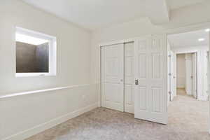 Unfurnished bedroom with light carpet and a closet