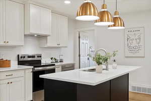 Kitchen with white cabinetry, a kitchen island with sink, and stainless steel electric range