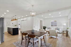 Dining room with light hardwood / wood-style floors, sink, and an inviting chandelier