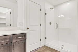 Bathroom featuring hardwood / wood-style floors, vanity, and walk in shower