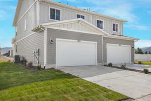 View of front facade with a front yard, a garage, and cooling unit