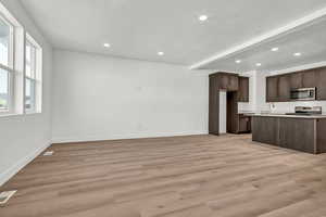 Kitchen with sink, a textured ceiling, dark brown cabinets, appliances with stainless steel finishes, and light wood-type flooring