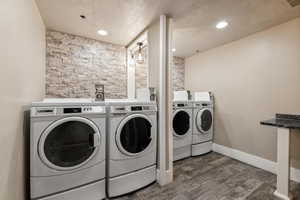 Clothes washing area with separate washer and dryer, dark wood-type flooring, and a textured ceiling