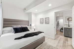 Bedroom with light hardwood / wood-style floors and connected bathroom