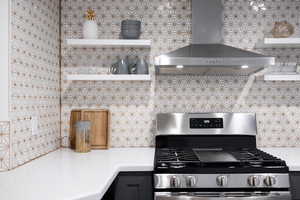 Kitchen featuring decorative backsplash, stainless steel range with gas cooktop, and wall chimney range hood