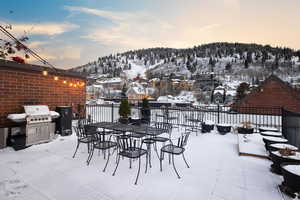 Snow covered patio featuring a mountain view and area for grilling