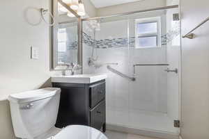 Bathroom featuring tile patterned flooring, a shower with door, vanity, and toilet