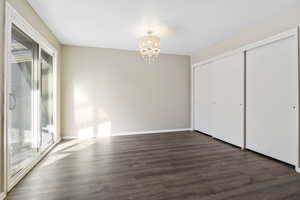 Master Bedroom featuring access to exterior, a notable chandelier, dark hardwood / wood-style flooring, and a closet