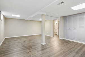 Basement with light wood-type flooring and wood walls