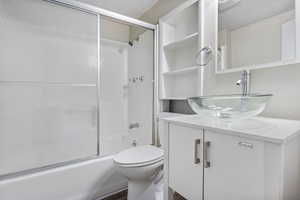 Main Floor Full bathroom featuring vanity, toilet, combined bath / shower with glass door, and wood-type flooring