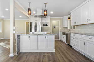 Kitchen featuring white cabinets, dark hardwood / wood-style floors, pendant lighting, a kitchen island, and appliances with stainless steel finishes