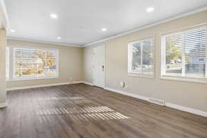 Unfurnished room featuring crown molding, a healthy amount of sunlight, and dark hardwood / wood-style floors