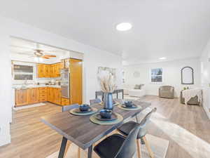 Dining space featuring ceiling fan, sink, and light wood-type flooring