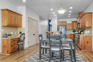 Dining space with a textured ceiling and light hardwood / wood-style flooring