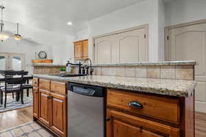 Kitchen featuring dishwasher, backsplash, sink, ceiling fan, and light wood-type flooring